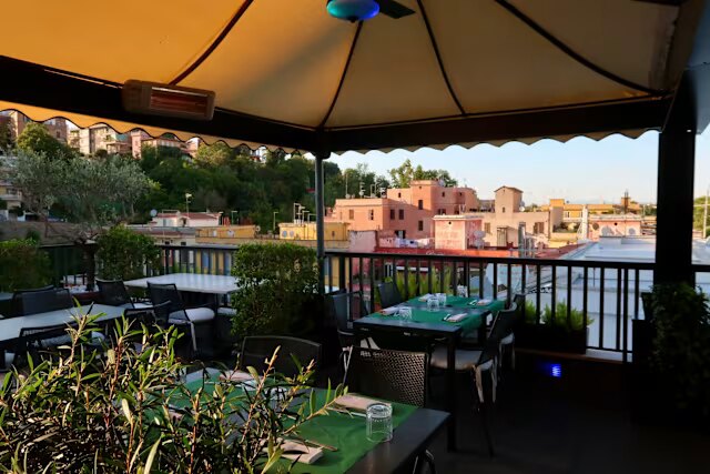 Vista al tramonto sui tetti di Roma con ombrellone e tavoli